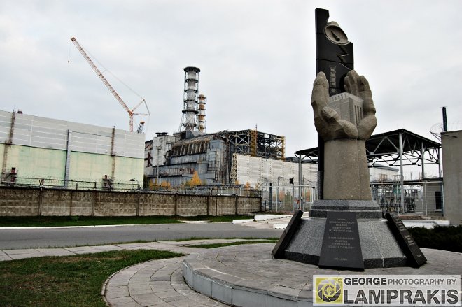 Το μνημείο και στο βάθος ο μοιραίος πυρηνικός αντιδραστήρας ν.4 του εργοστασίου στο Τσερνομπίλ.